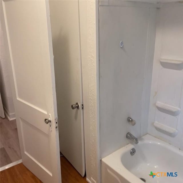 bathroom featuring washtub / shower combination and wood-type flooring