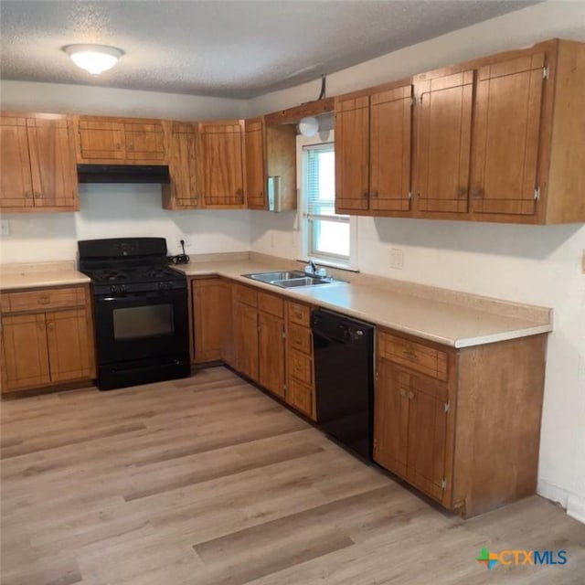 kitchen featuring black appliances, light wood-type flooring, sink, and a textured ceiling