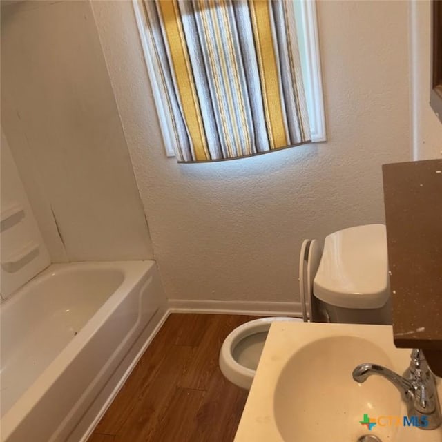 bathroom with hardwood / wood-style flooring, toilet, and sink