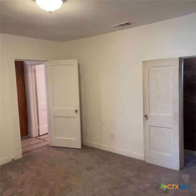 carpeted empty room featuring a textured ceiling