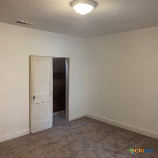 spare room featuring dark colored carpet and a textured ceiling