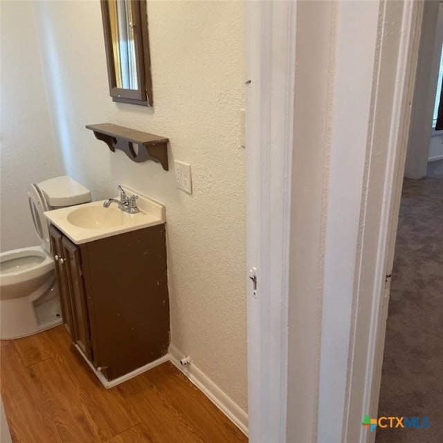 bathroom with hardwood / wood-style floors, vanity, and toilet