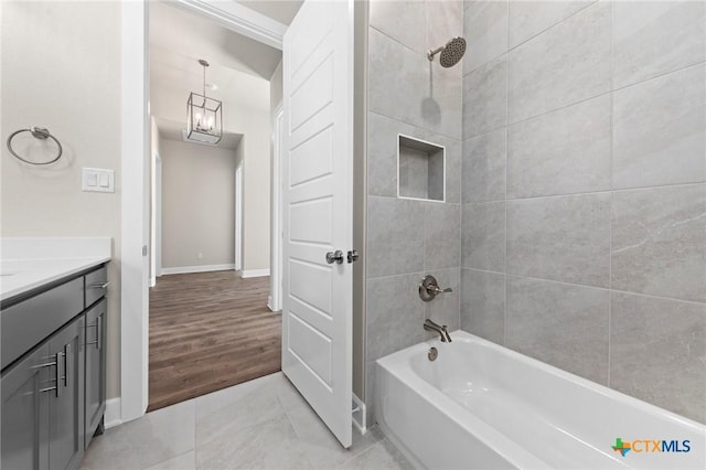 full bathroom featuring a notable chandelier, bathing tub / shower combination, vanity, and baseboards