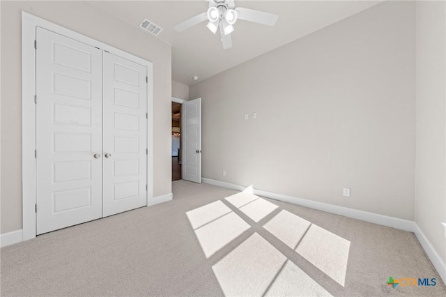 unfurnished bedroom with a closet, visible vents, light carpet, and baseboards