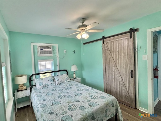 1208 W Adams St, Port Oconnor, TX 77982 - bedroom with a barn door, dark wood-style floors, ceiling fan, and a wall mounted AC