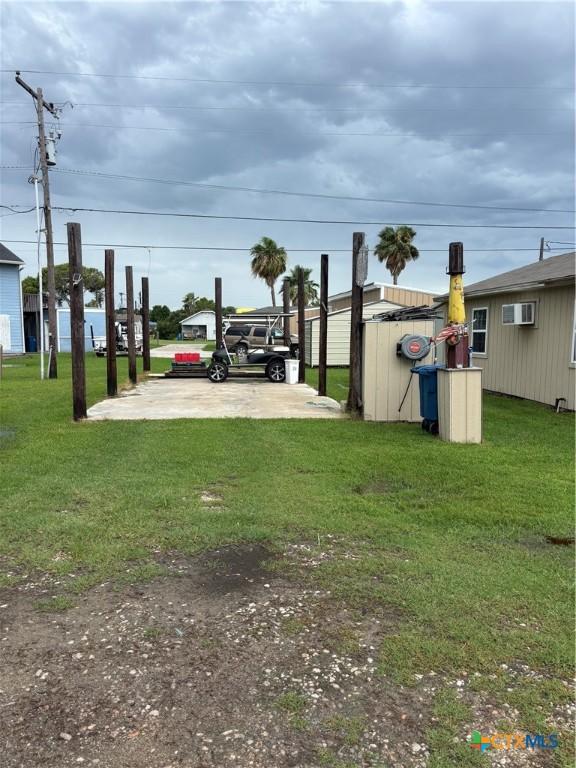 1208 W Adams St, Port Oconnor, TX 77982 - view of grassy yard featuring a wall unit AC and an outdoor structure
