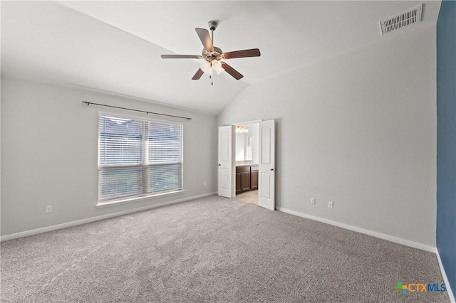 unfurnished bedroom featuring light carpet, ensuite bathroom, vaulted ceiling, and ceiling fan