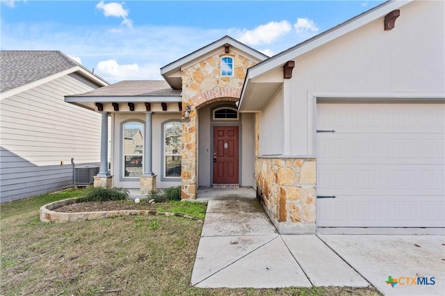 entrance to property featuring a lawn, cooling unit, and a garage