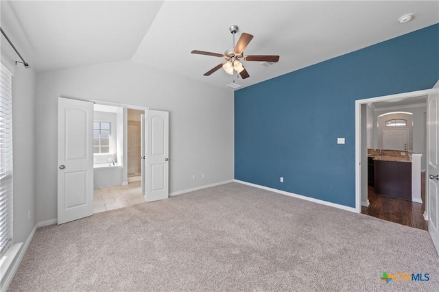 unfurnished bedroom with carpet flooring, ensuite bath, ceiling fan, and vaulted ceiling