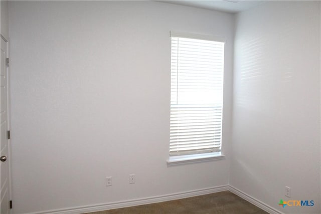 empty room with a wealth of natural light and dark colored carpet