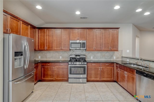 7400 Longford Trl, Austin, TX 78754 - kitchen featuring stainless steel appliances, dark stone counters, brown cabinetry, backsplash, and recessed lighting