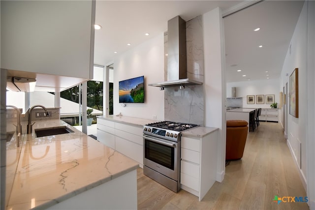 kitchen featuring light stone counters, extractor fan, high end stainless steel range oven, backsplash, and white cabinetry