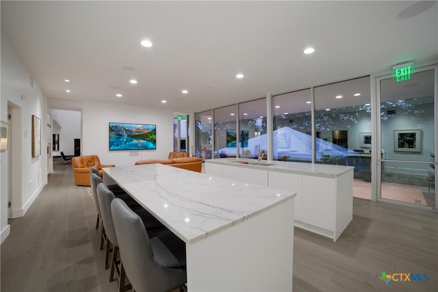 kitchen featuring a kitchen island, a wall of windows, hardwood / wood-style floors, and white cabinetry