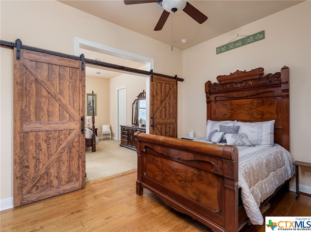 bedroom featuring ceiling fan, a barn door, and light hardwood / wood-style floors