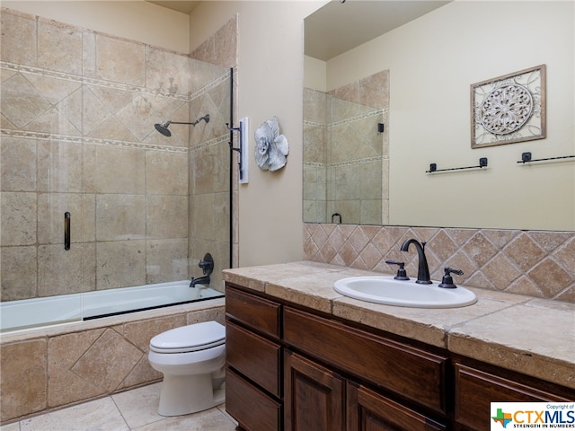 full bathroom with tile patterned floors, toilet, shower / bath combination with glass door, vanity, and backsplash