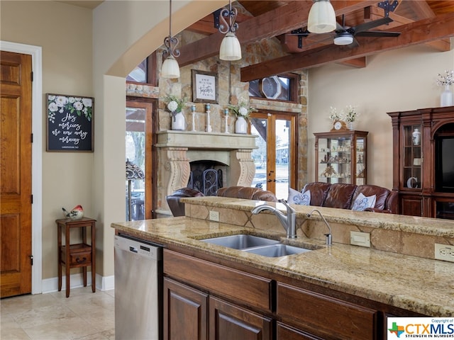 kitchen with decorative light fixtures, beamed ceiling, dishwasher, sink, and light stone countertops