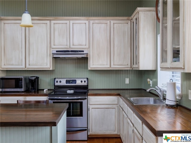 kitchen featuring appliances with stainless steel finishes, pendant lighting, light brown cabinetry, butcher block countertops, and sink