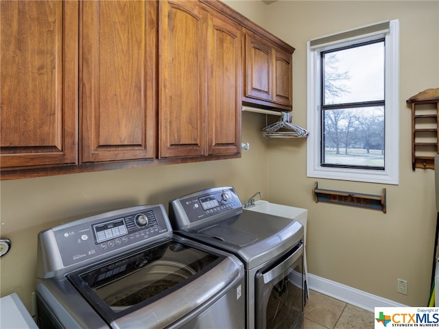 laundry room with washing machine and dryer, cabinets, and light tile patterned flooring