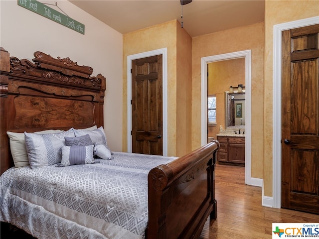 bedroom with light hardwood / wood-style floors and ensuite bath