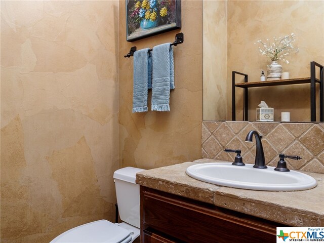 bathroom with vanity, backsplash, and toilet