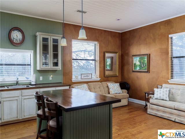 kitchen with a kitchen breakfast bar, sink, pendant lighting, and light wood-type flooring