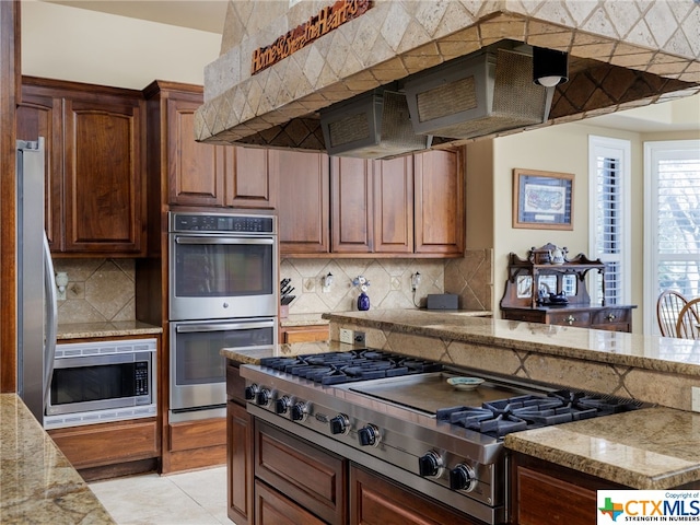 kitchen with appliances with stainless steel finishes, light stone countertops, decorative backsplash, and light tile patterned floors