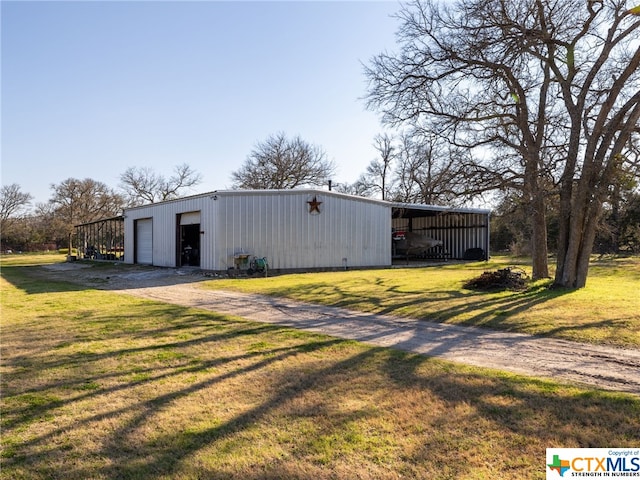 view of outdoor structure featuring a carport, a garage, and a lawn