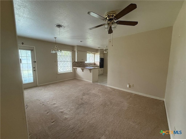 unfurnished living room featuring a textured ceiling, a healthy amount of sunlight, and light colored carpet