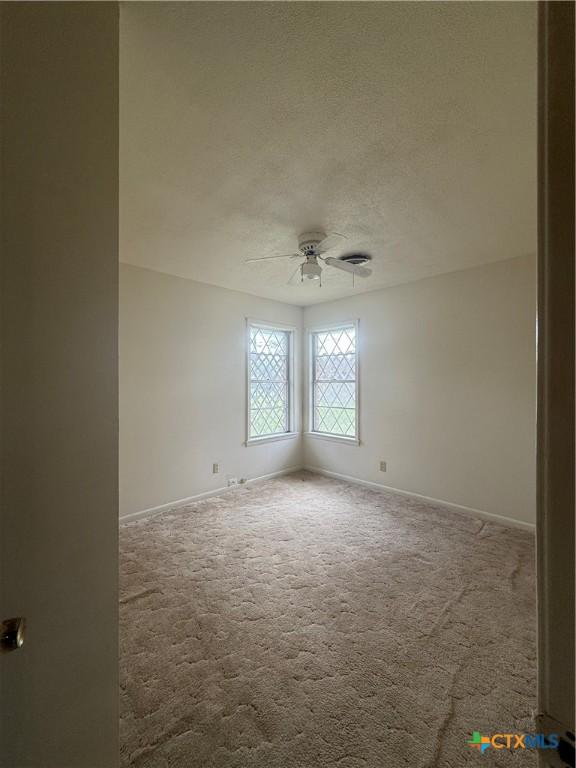 carpeted empty room featuring ceiling fan and a textured ceiling