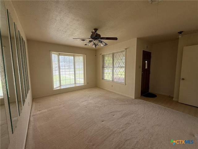 unfurnished room featuring ceiling fan, light colored carpet, and a textured ceiling