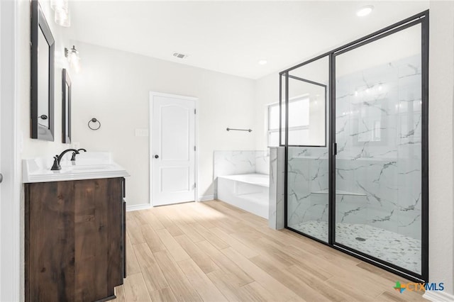 bathroom featuring independent shower and bath, vanity, and wood-type flooring