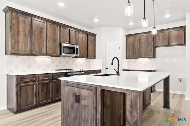 kitchen featuring pendant lighting, sink, dark brown cabinetry, and stainless steel appliances