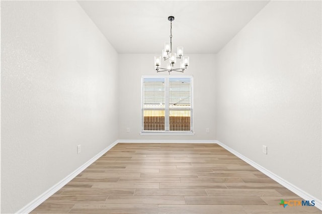 unfurnished dining area featuring light hardwood / wood-style flooring and an inviting chandelier