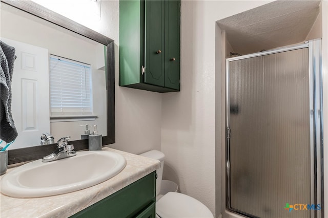 bathroom featuring vanity, toilet, an enclosed shower, and a textured ceiling