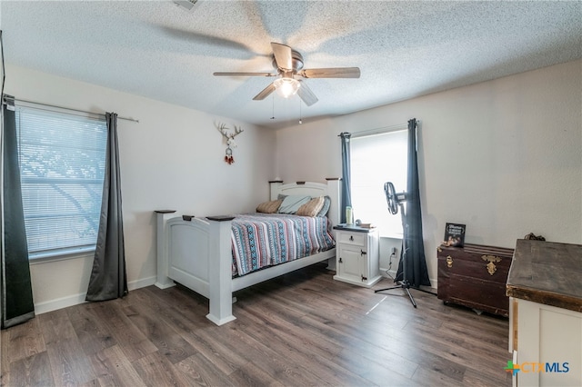 bedroom with a textured ceiling, ceiling fan, and dark hardwood / wood-style floors