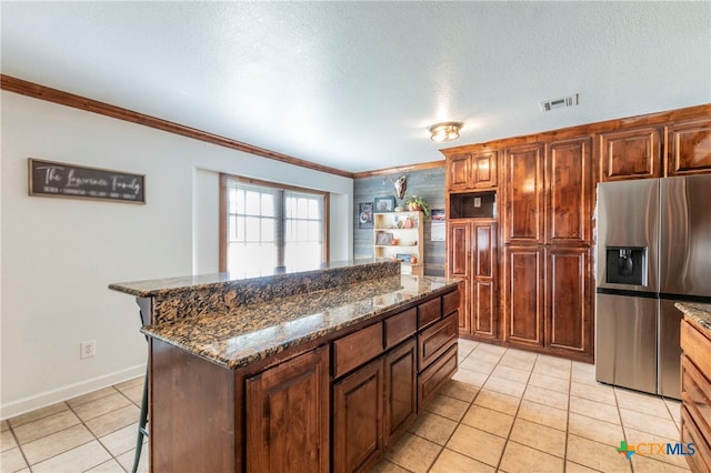 kitchen with crown molding, a kitchen island, stainless steel refrigerator with ice dispenser, a kitchen breakfast bar, and dark stone countertops