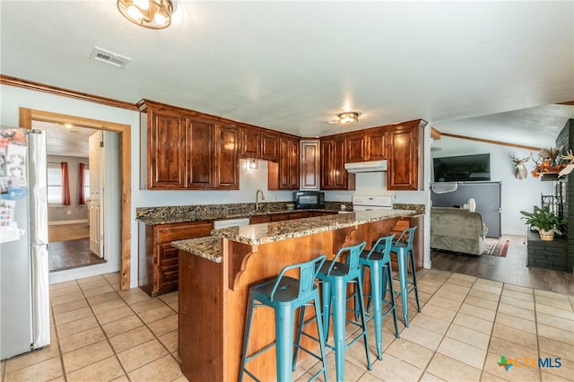 kitchen with a kitchen island, dark stone countertops, refrigerator, white electric range, and light hardwood / wood-style flooring