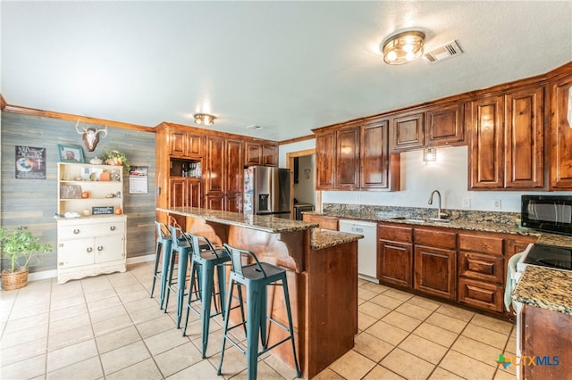 kitchen featuring sink, light stone countertops, a center island, stainless steel fridge, and dishwasher