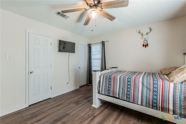 bedroom with dark wood-type flooring, a textured ceiling, and ceiling fan