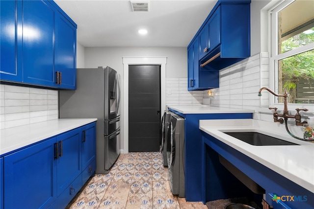 1910 S Rainbow Ranch Rd, Wimberley, TX 78676 - kitchen with washer and dryer, a sink, stainless steel fridge with ice dispenser, blue cabinetry, and light countertops