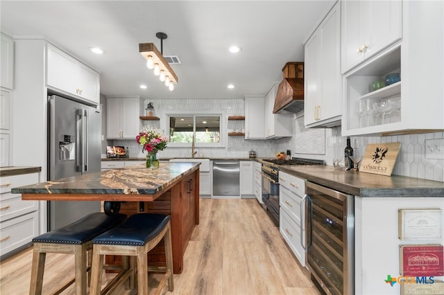 1910 S Rainbow Ranch Rd, Wimberley, TX 78676 - kitchen featuring open shelves, wine cooler, dark countertops, high quality appliances, and a breakfast bar