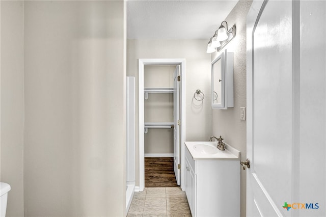 bathroom with a textured ceiling, vanity, hardwood / wood-style flooring, and toilet