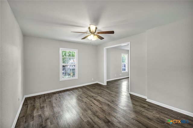 empty room with ceiling fan, dark hardwood / wood-style floors, and a healthy amount of sunlight