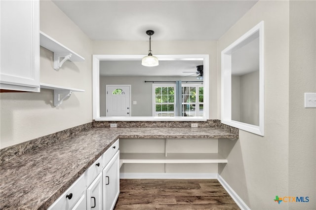 kitchen featuring white cabinets, dark wood-type flooring, built in desk, and ceiling fan