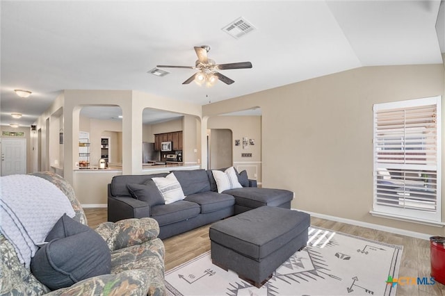 living room featuring vaulted ceiling, light wood-style flooring, and visible vents