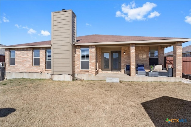 back of property with brick siding, a chimney, a patio area, and fence