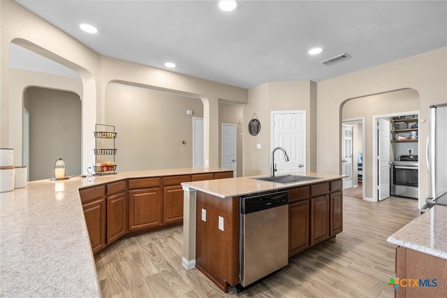 kitchen featuring a center island with sink, visible vents, range, stainless steel dishwasher, and a sink