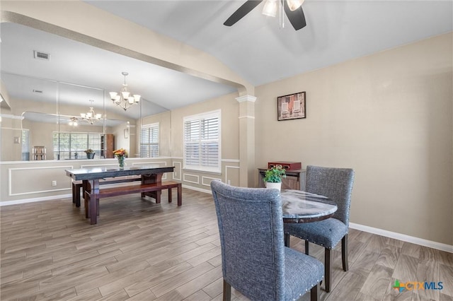 dining space with light wood finished floors, baseboards, visible vents, vaulted ceiling, and ceiling fan with notable chandelier