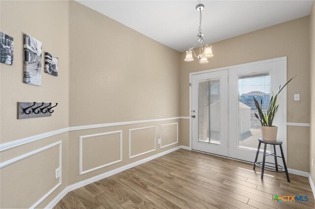 dining room with a chandelier, wainscoting, wood finished floors, and a decorative wall