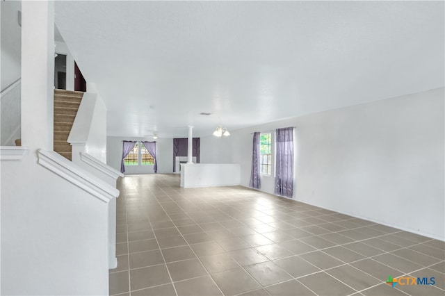 unfurnished living room featuring a wealth of natural light, a notable chandelier, and tile patterned floors